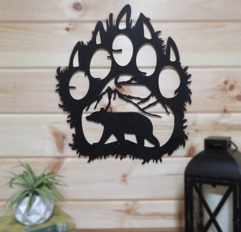 Bear paw print with mountain and bear silhouette painted black on pine wall.