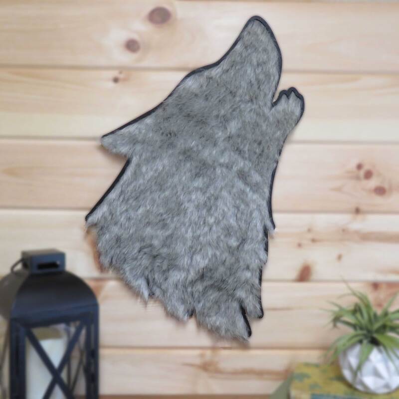 Wood wolf head silhouette painted black with faux fur insert and hung on pine wall.